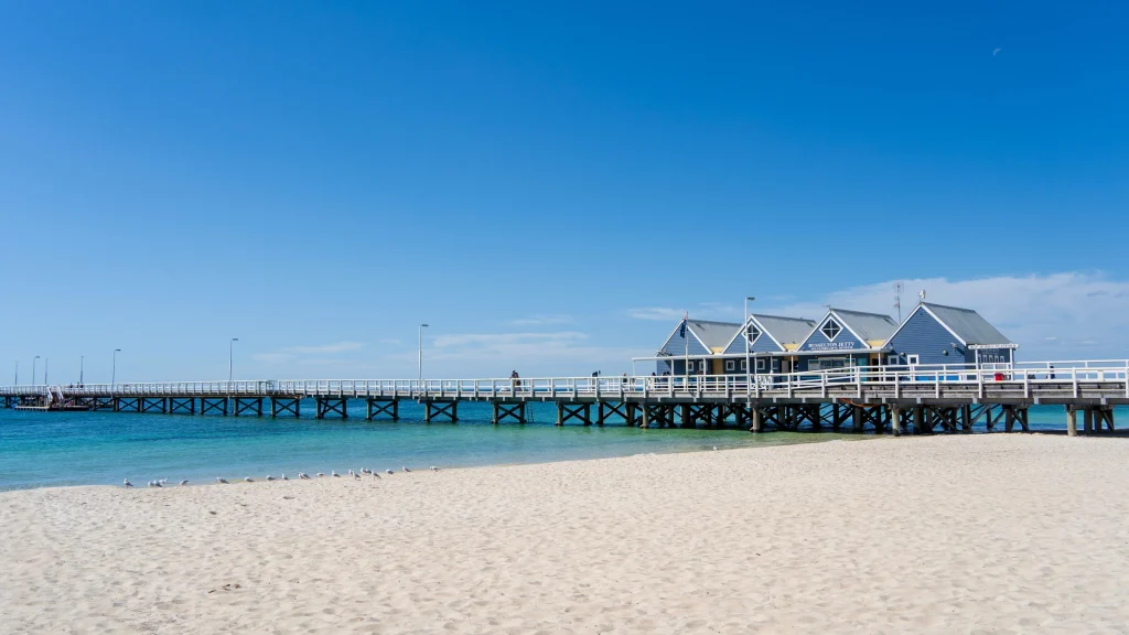 The Busselton Jetty reaching out over shallow water from the beach.