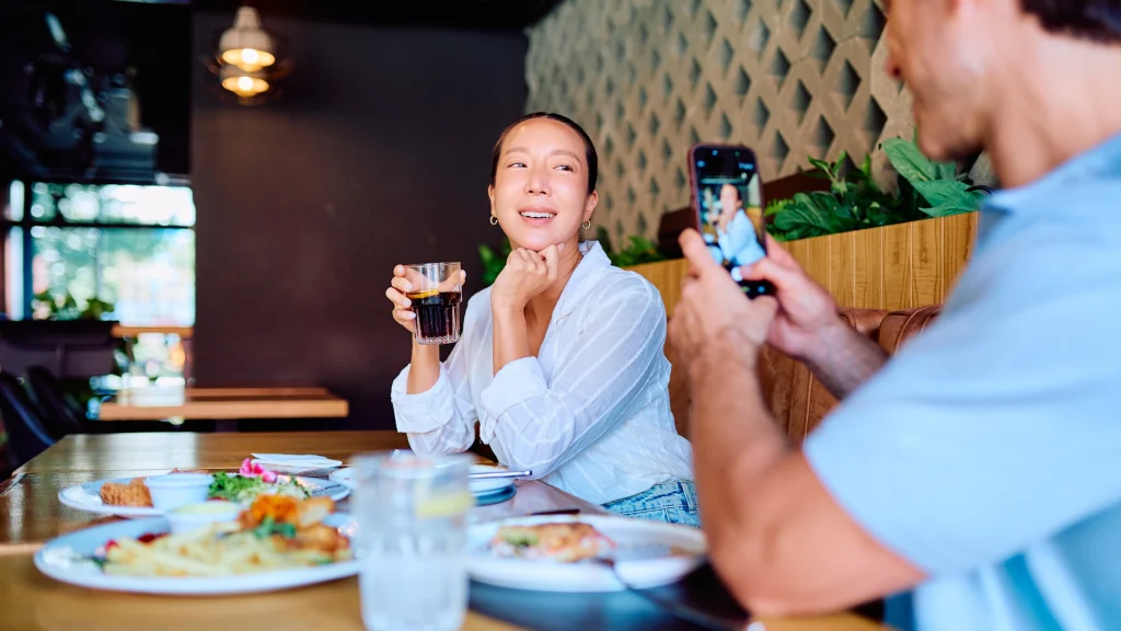 A diner photographing their meal on a phone across a restaurant table.